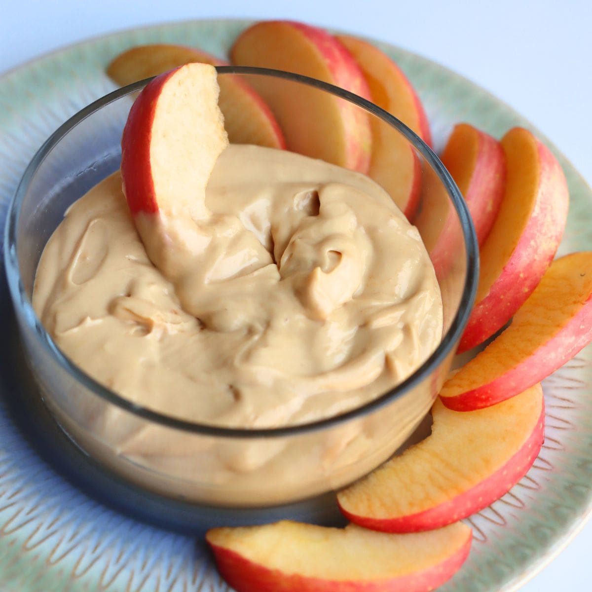 peanut butter dip for apples with apples on a plate