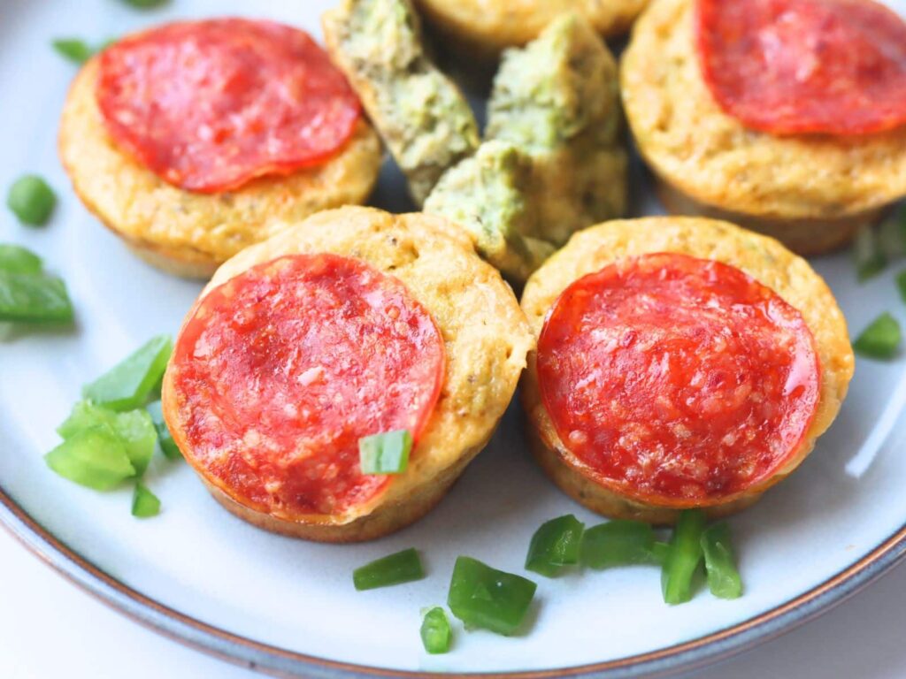 high protein mini pizza muffins on a plate with chopped green onion