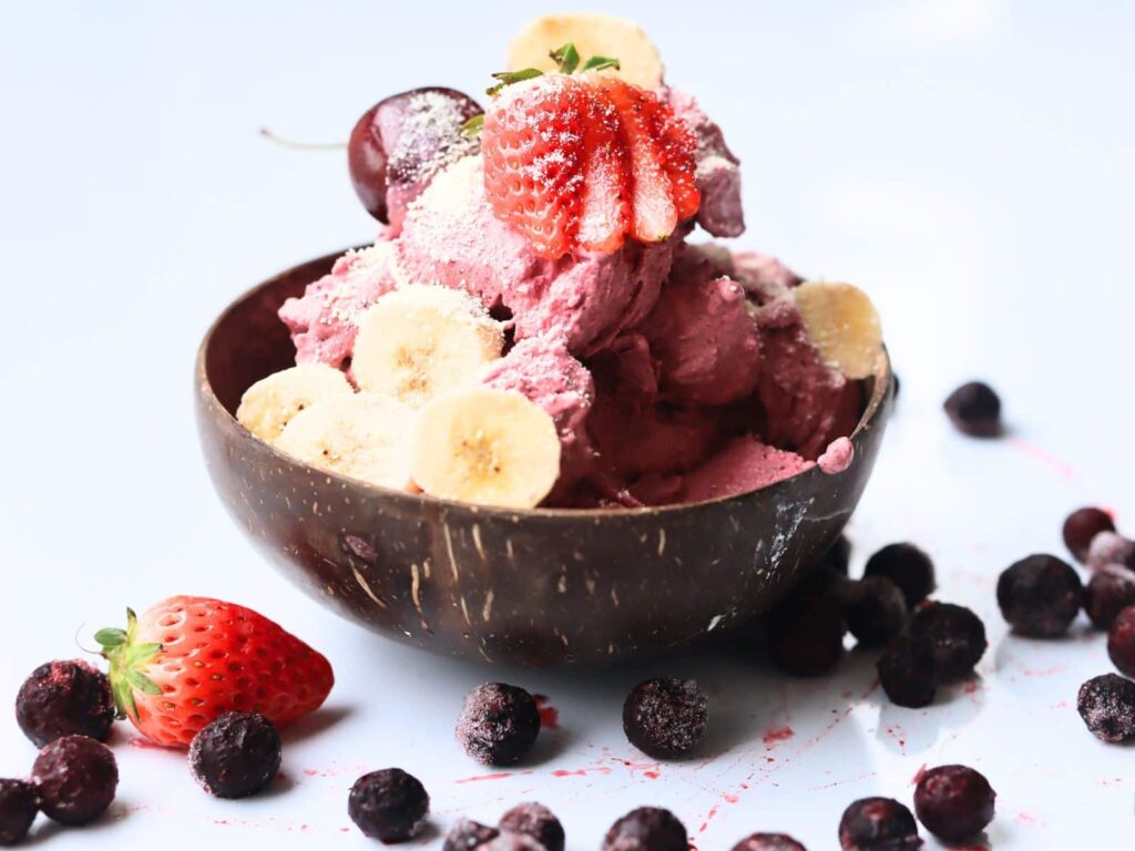 acai ice cream in a coconut wood bowl with mixed berries on top