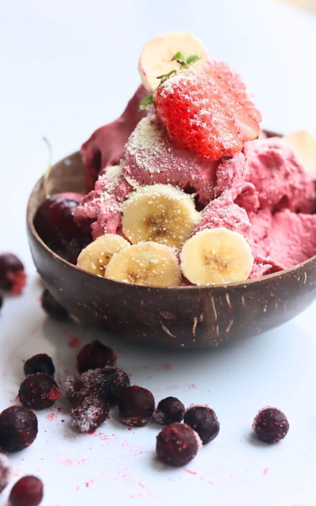 acai ice cream in a coconut wood bowl with mixed berries on top