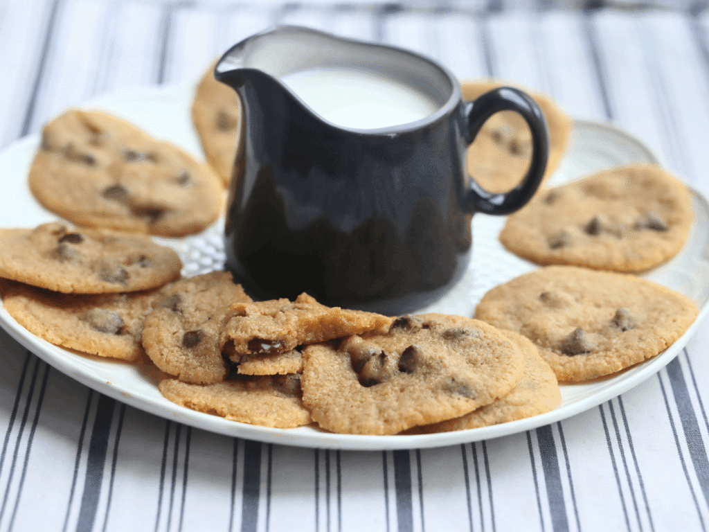 a plate of soft-baked whole wheat chocolate chip cookies with a pitcher of milk