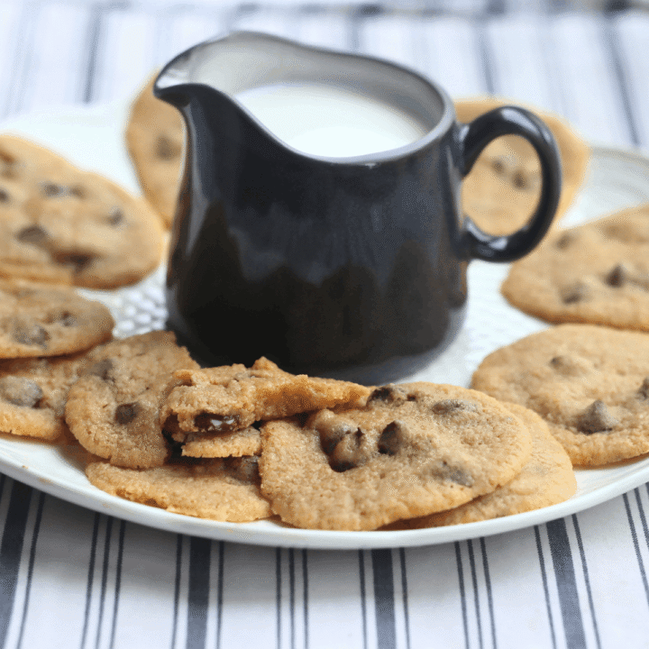 a plate of soft-baked whole wheat chocolate chip cookies with a pitcher of milk