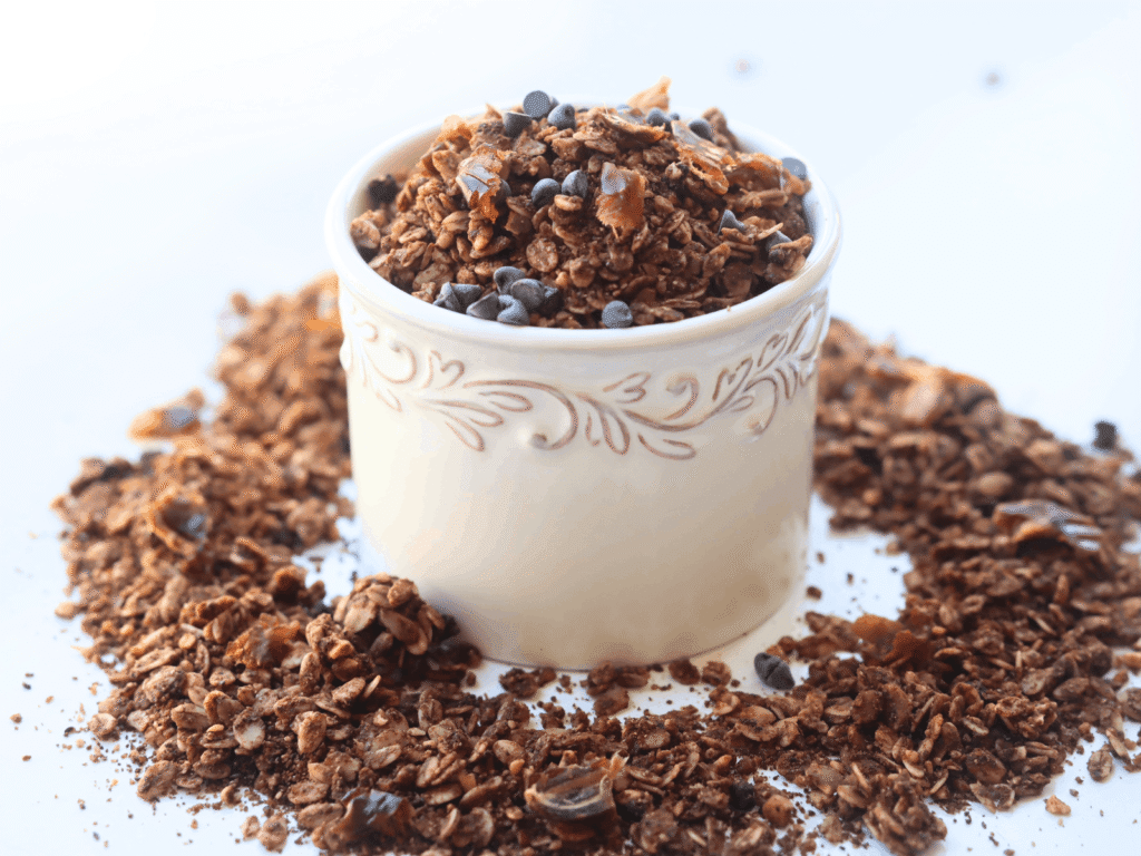 chocolate granola with chocolate chips and dates in a white bowl