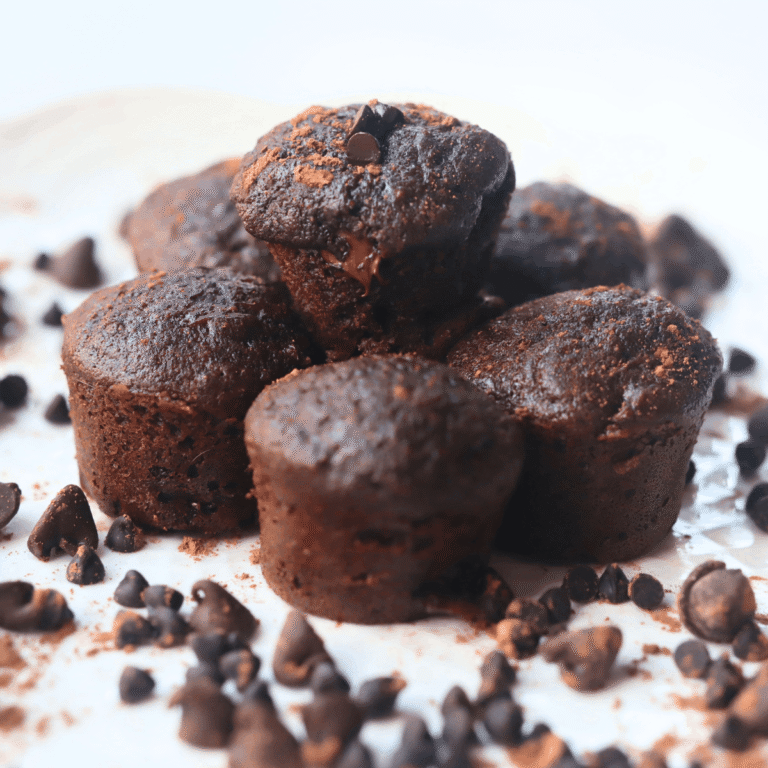 a stack of chocolate mini muffins made with whole wheat flour and zucchini surrounded by chocolate chips